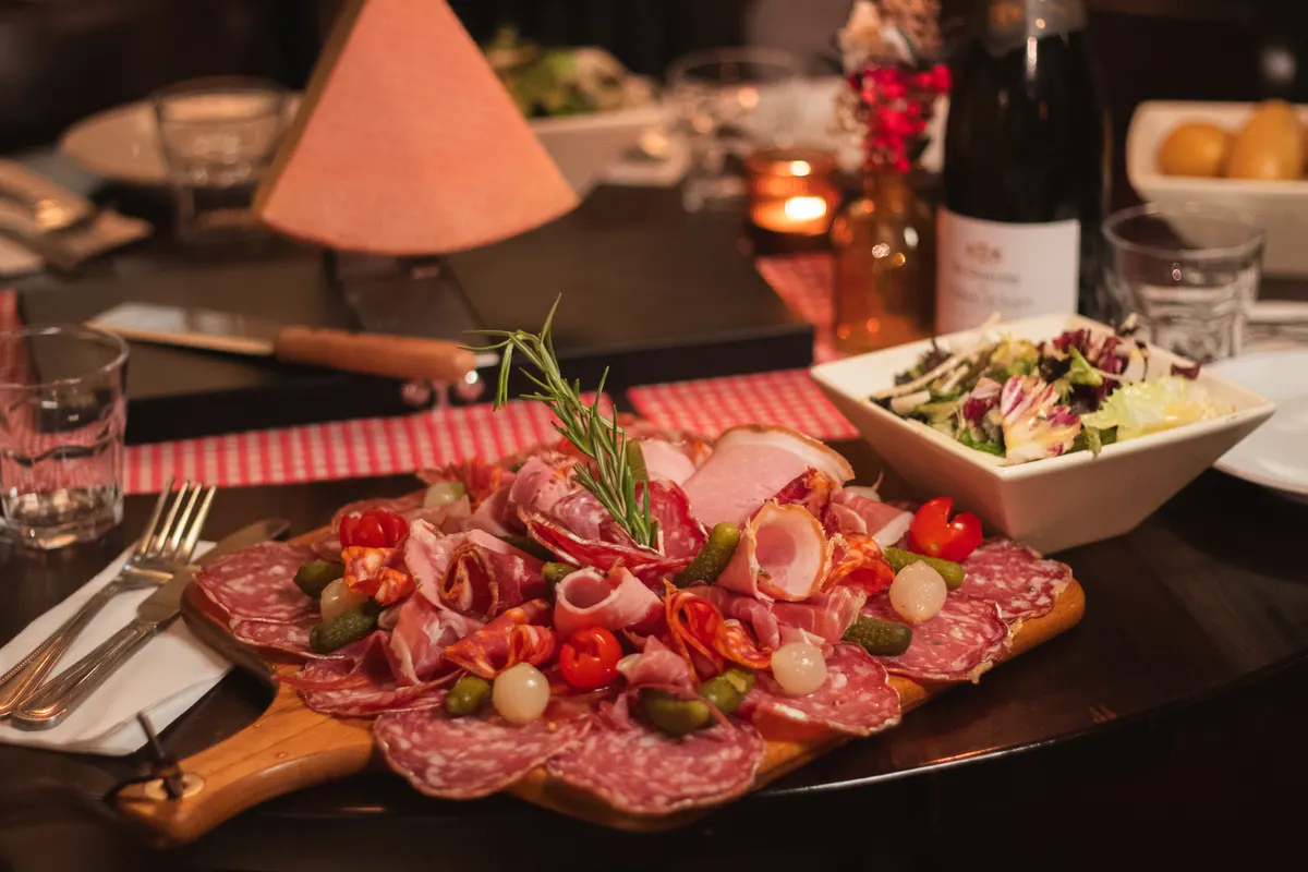A board of French and Italian charcuterie beside the raclette