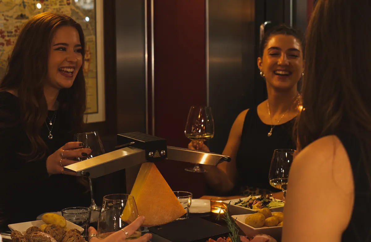Friends laughing together around the raclette at Chez Bernard