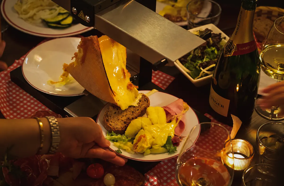 A plate of potatoes, bread and charcuterie under melting raclette
