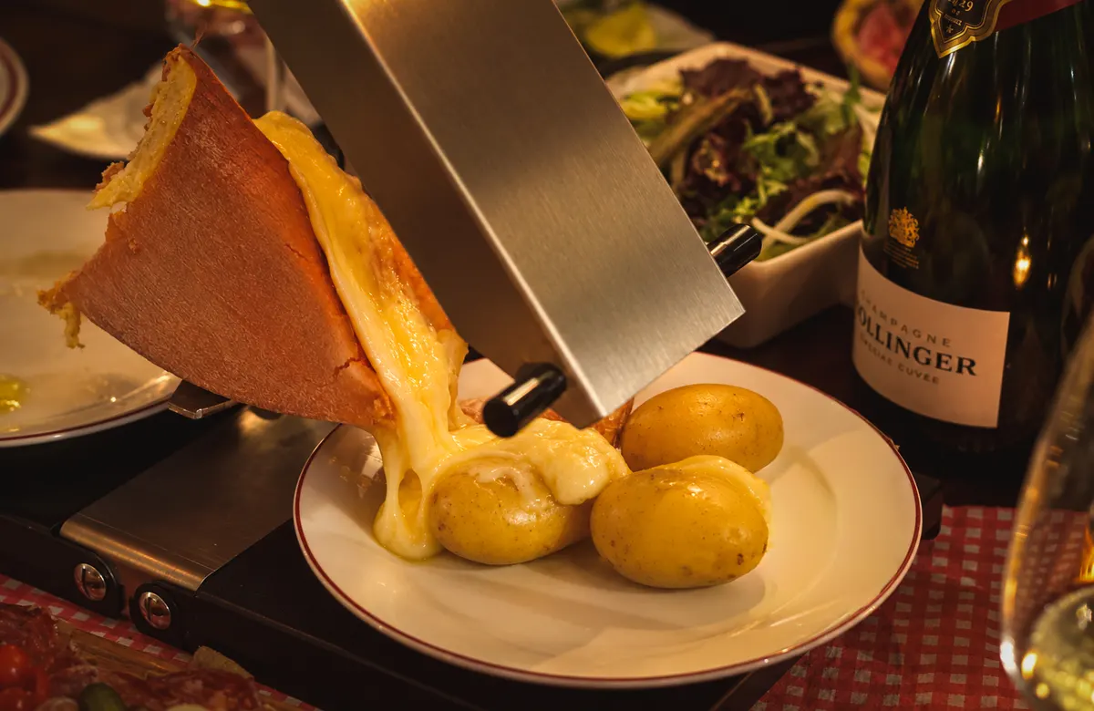 Raclette sliding off the wheel onto a plate of potatoes