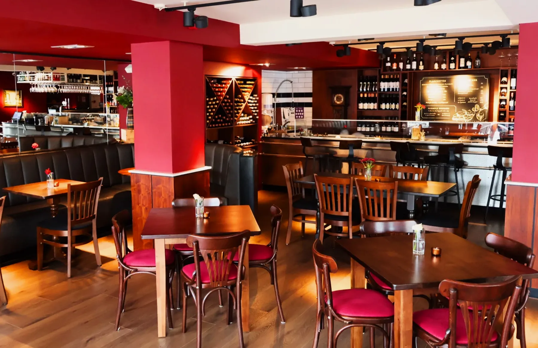 The dining room at Chez Bernard set for service, with red pillars and bentwood chairs